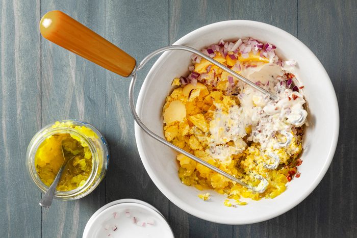 Egg yolks onions and crumbled bacon mixed in small bowl