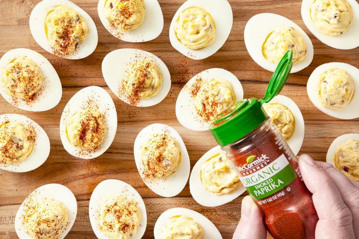 Sprinkling paprika on top of each deviled egg