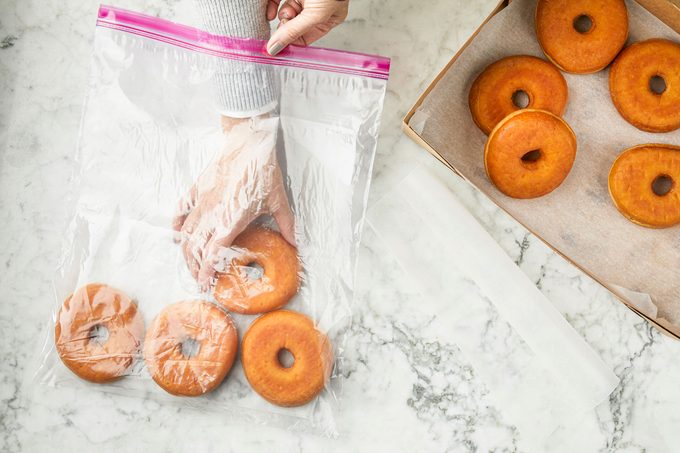 hands adding doughnuts to a plastic bag for freezing