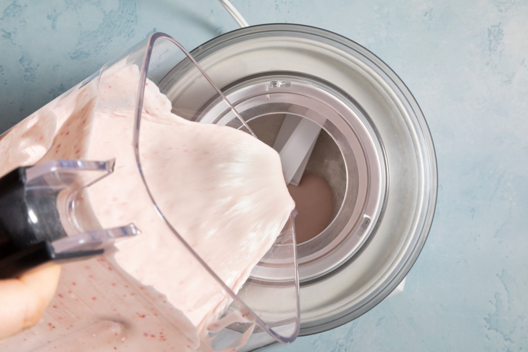 Pouring the strawberry puree into the cream mixture.