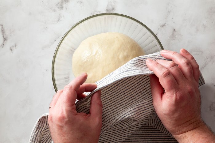 Covering the dough resting in glass bowl