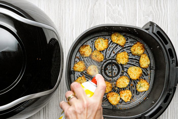 overhead shot of cooking spray spritz on pickles in the air fryer