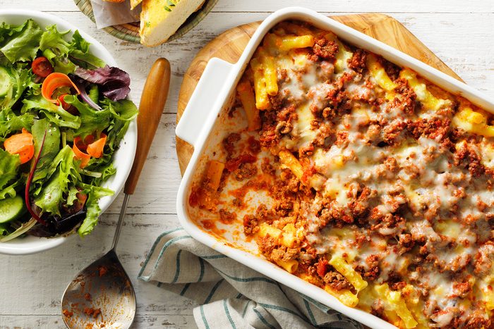A casserole dish with pasta and meat and a salad