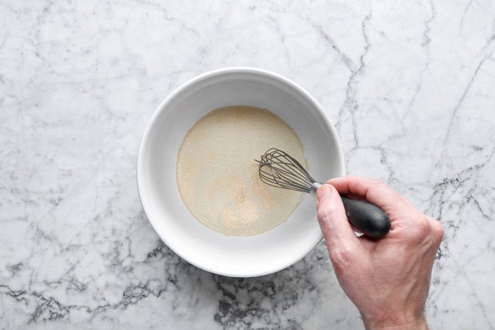 Mixing Yeast in warm water wit spatula in a large bowl