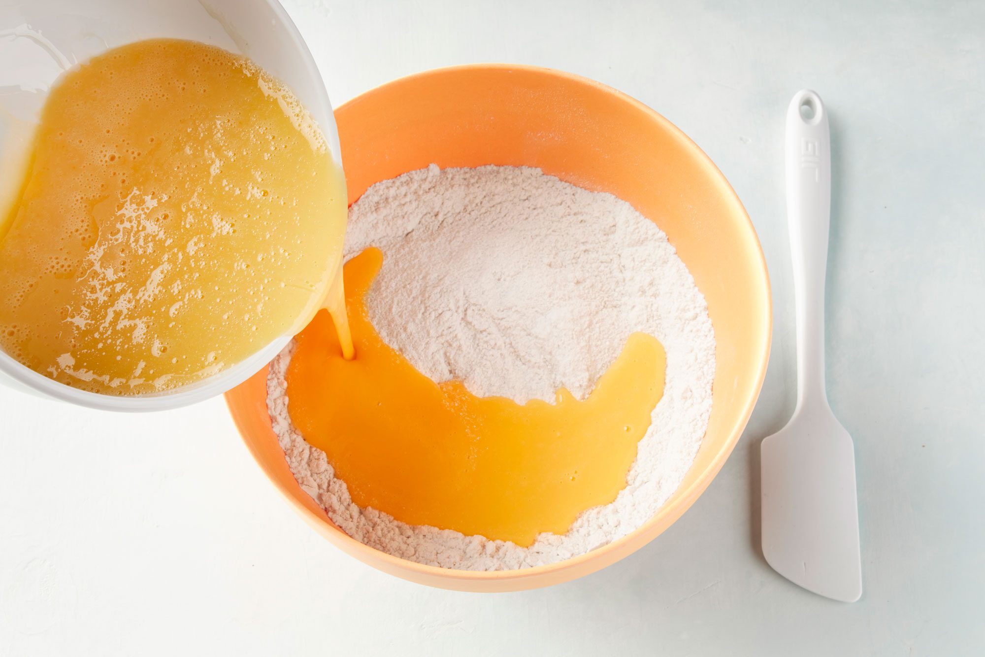 overhead shot of pouring whisked eggs into flour mix