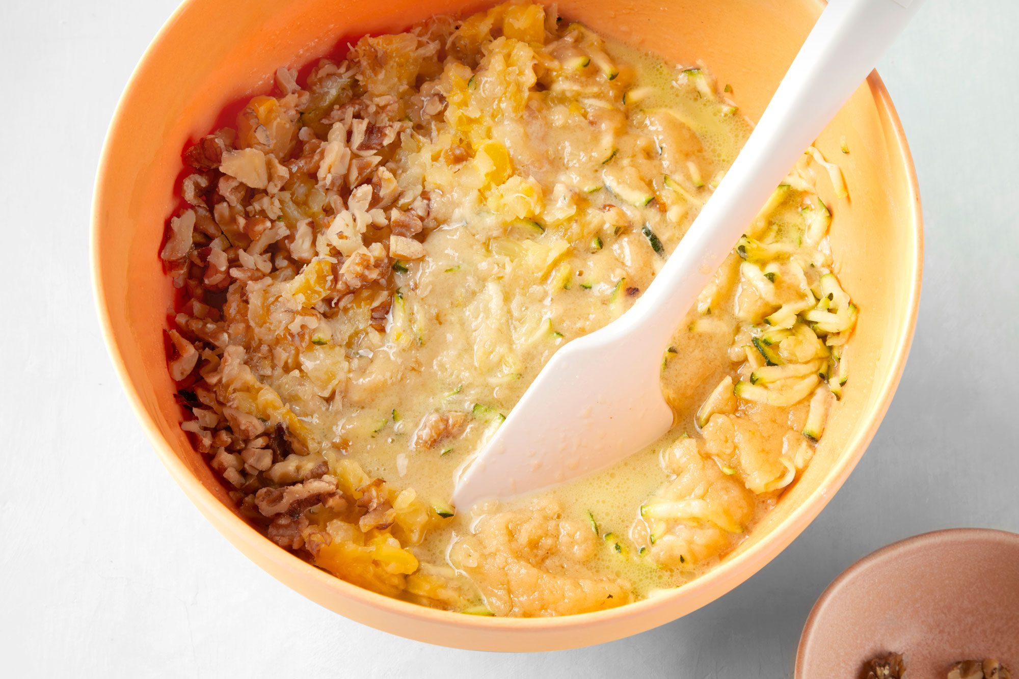 high angle shot of walnuts mixed in the pina colada zucchini bread batter