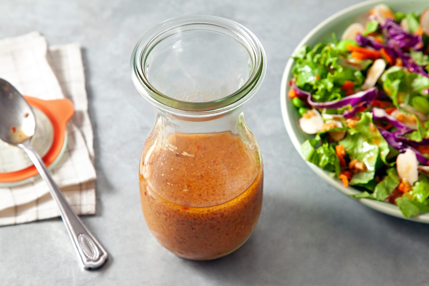 A jar of Asian Salad dressing with a bowl of salad