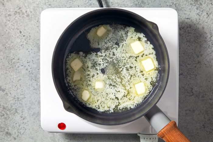 Overhead shot of a small saucepan; melt butter over medium heat; induction; marble background;
