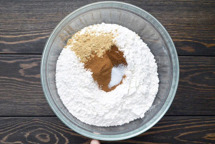 A glass bowl of dry mixture on a wooden table