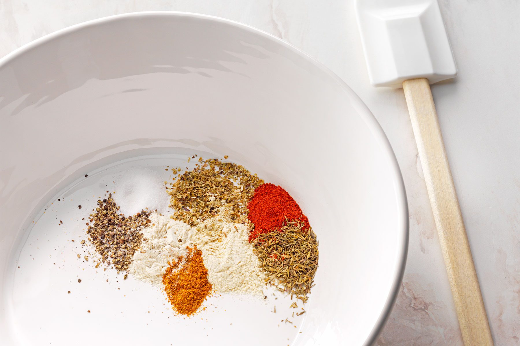 Top shot of combined the first 8 ingredients in a large bowl; spatula; white marble background;