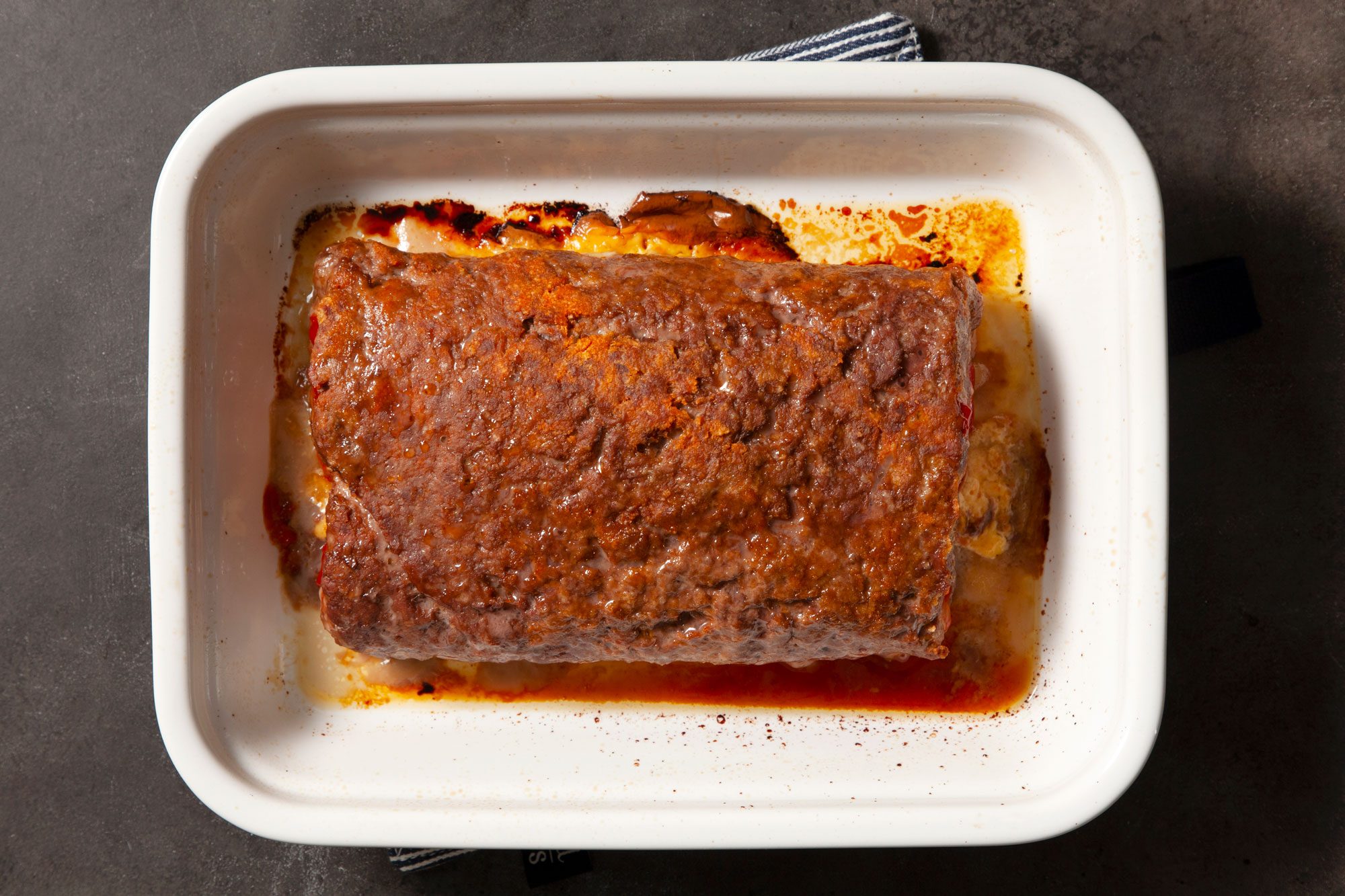 Overhead shot of Cheesebuger Meat Loaf; in baking pan; white and black line base cloth; black texture background;