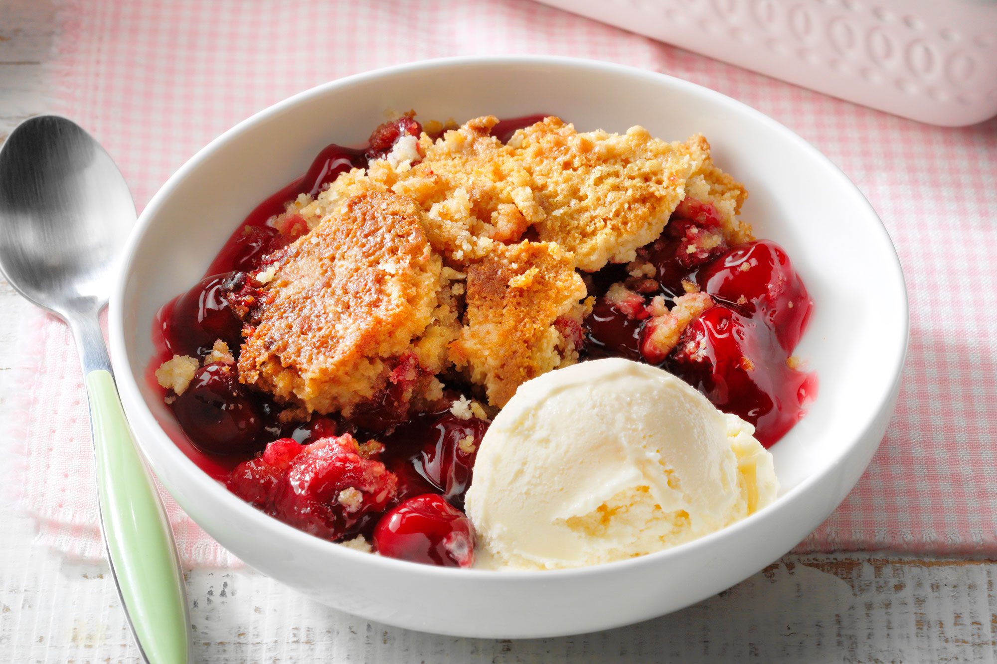 Cherry Dump Cake scooped out and served with vanilla ice cream in a bowl. Main focus on single serve