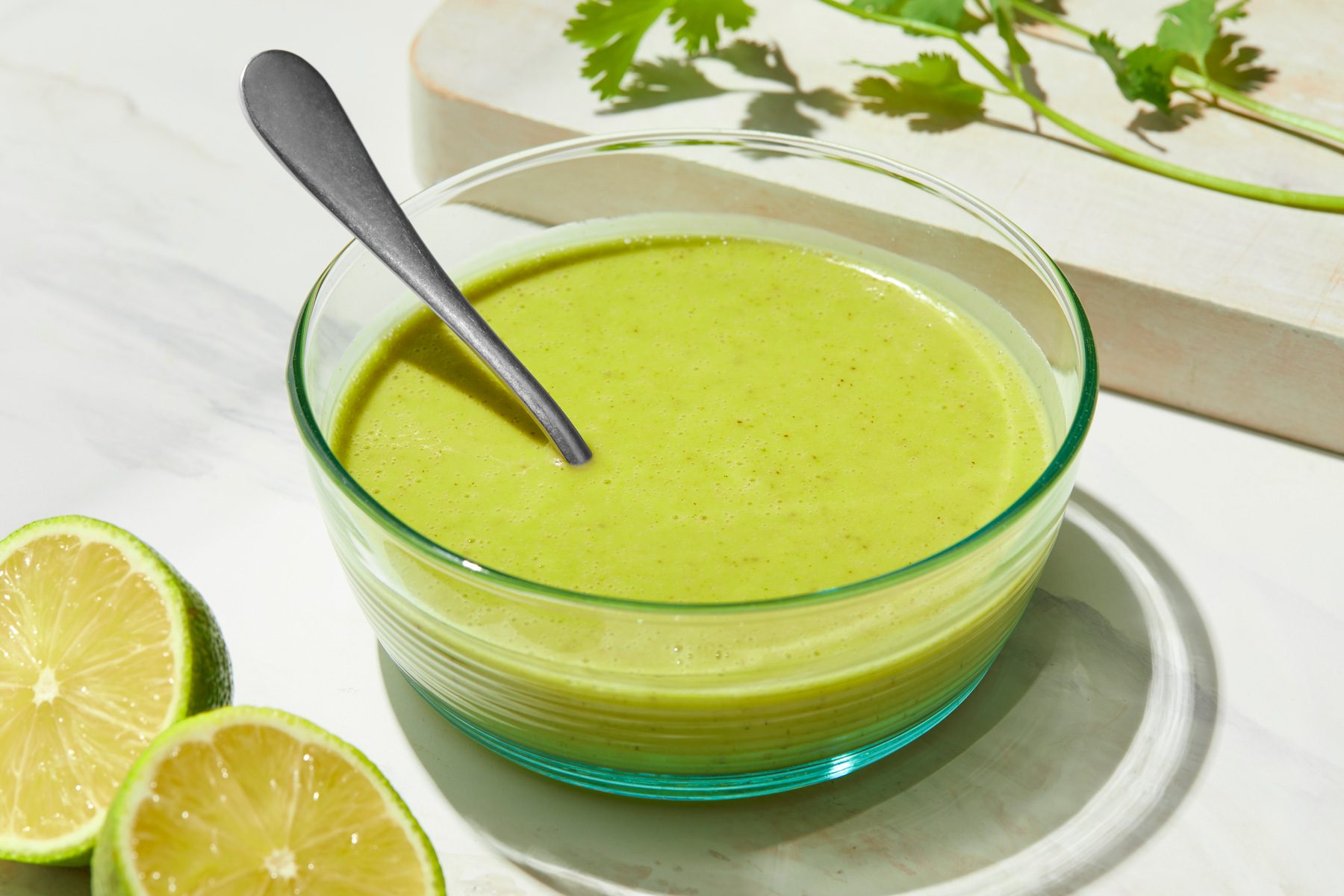 A glass bowl of Cilantro Lime Dressing with a spoon