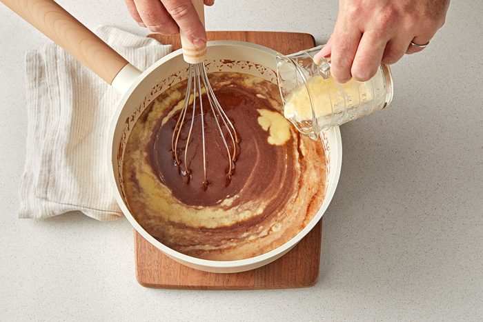 overhead shot of eggs adding in the cocoa batter in a saucepan