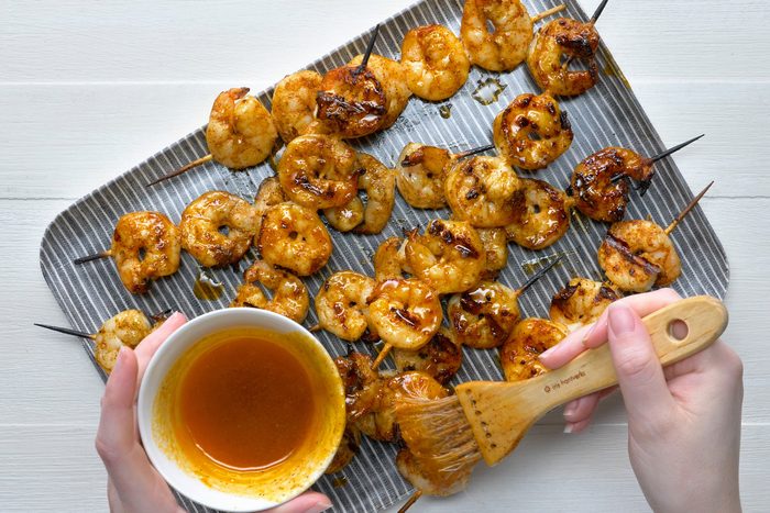 Brushing butter mixture over cooked shrimps