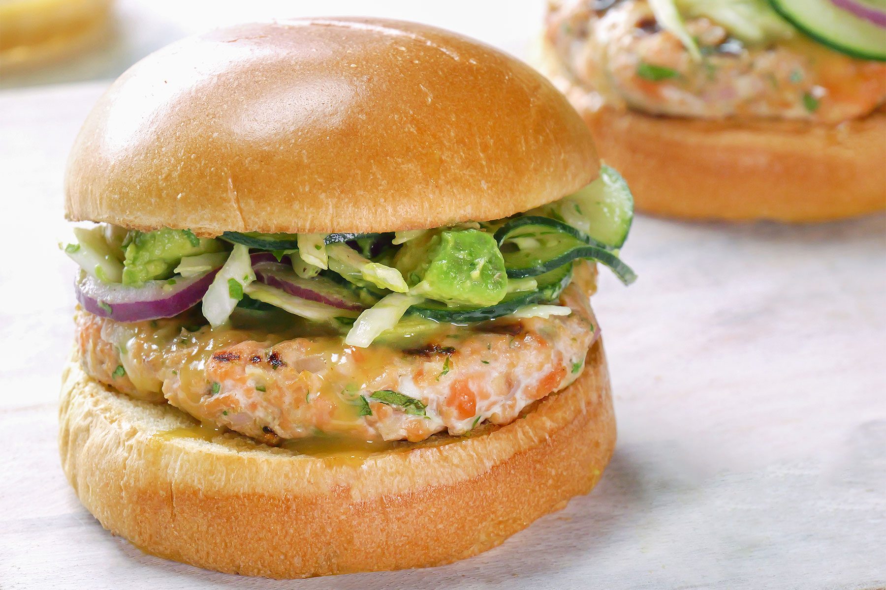 Close shot of Salmon Burgers with Tangy Slaw; wooden board;