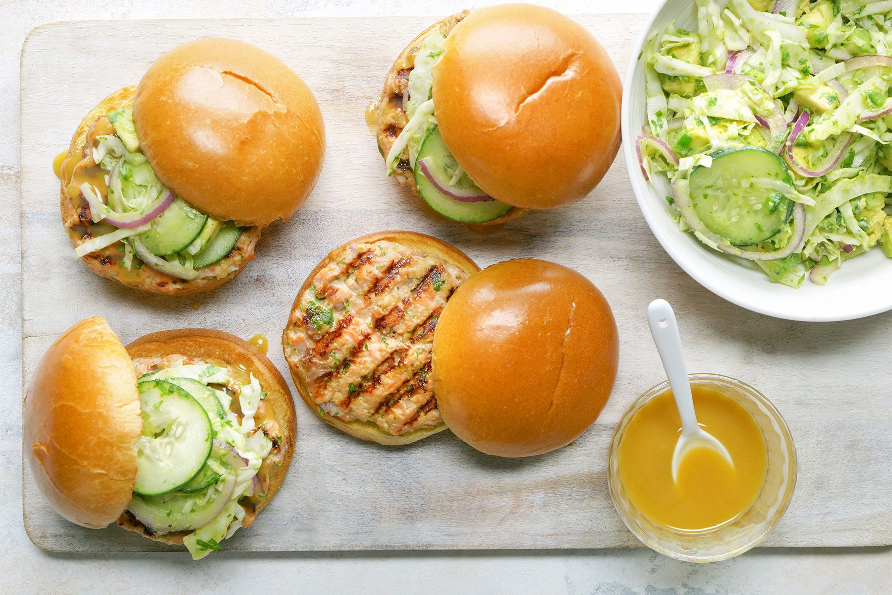 Close shot of Salmon Burgers with Tangy Slaw; wooden board; marble background;