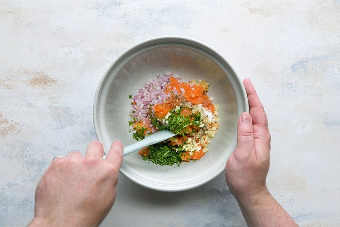 Overhead shot of bowl; add shallot; cilantro; soy sauce; honey garlic; salt and pepper; mix well; spatula; white marble background;