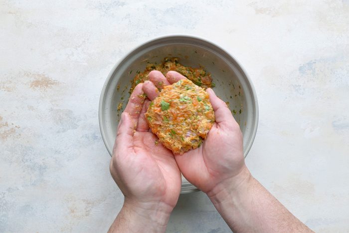 Overhead shot of shape the mixture into four thick patties; white marble background;