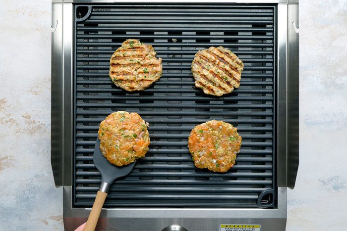 Overhead shot of griller; grill patties overv medium heat; heat 4-5 mintues on each sides; flat spatual; white marble background;