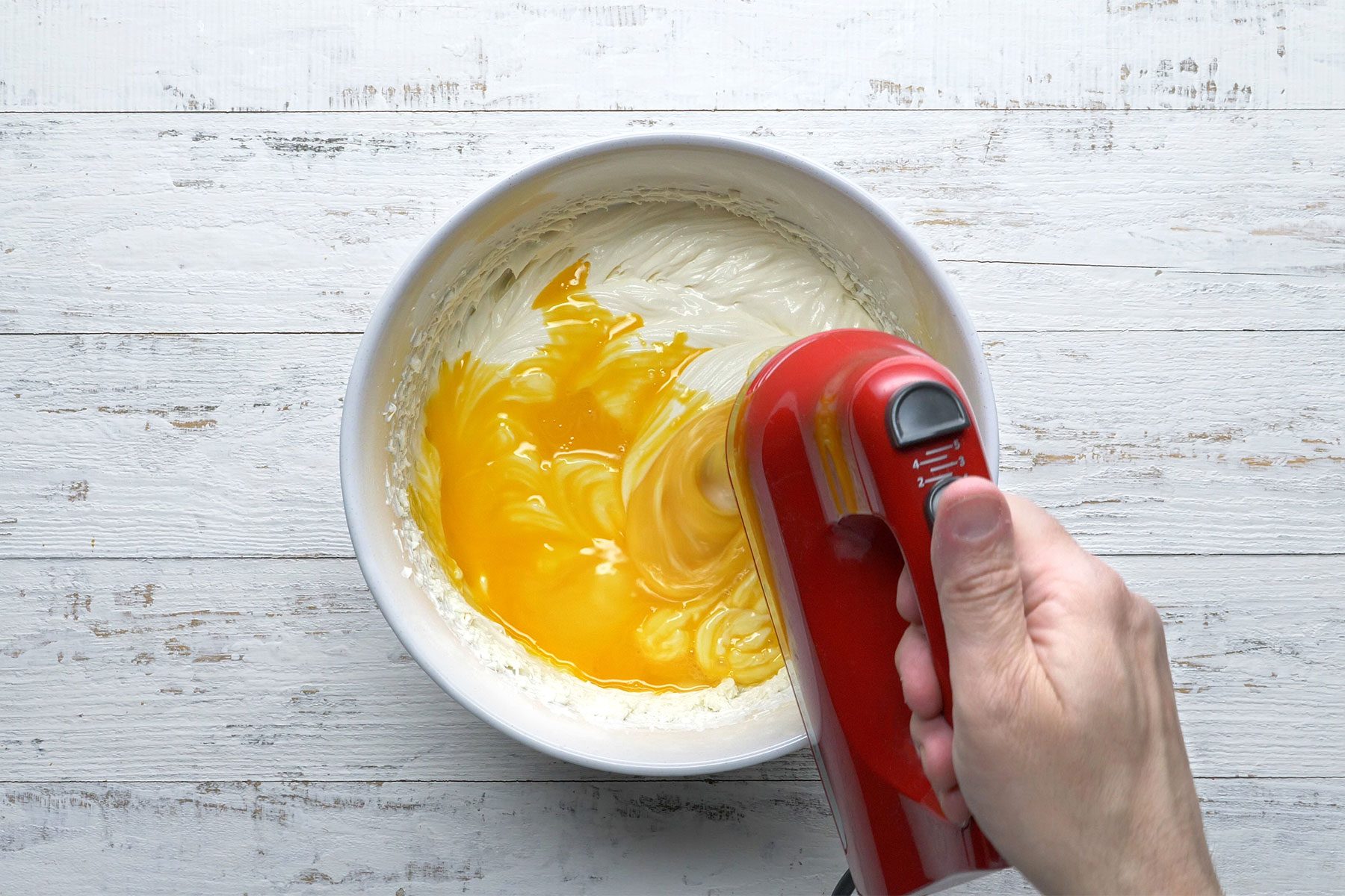 Overhead shot of a large bowl; beat cream cheese and sugar until smooth; beat in lemon juice and vanilla; add eggs; beat on low speed just until blended; wooden background;