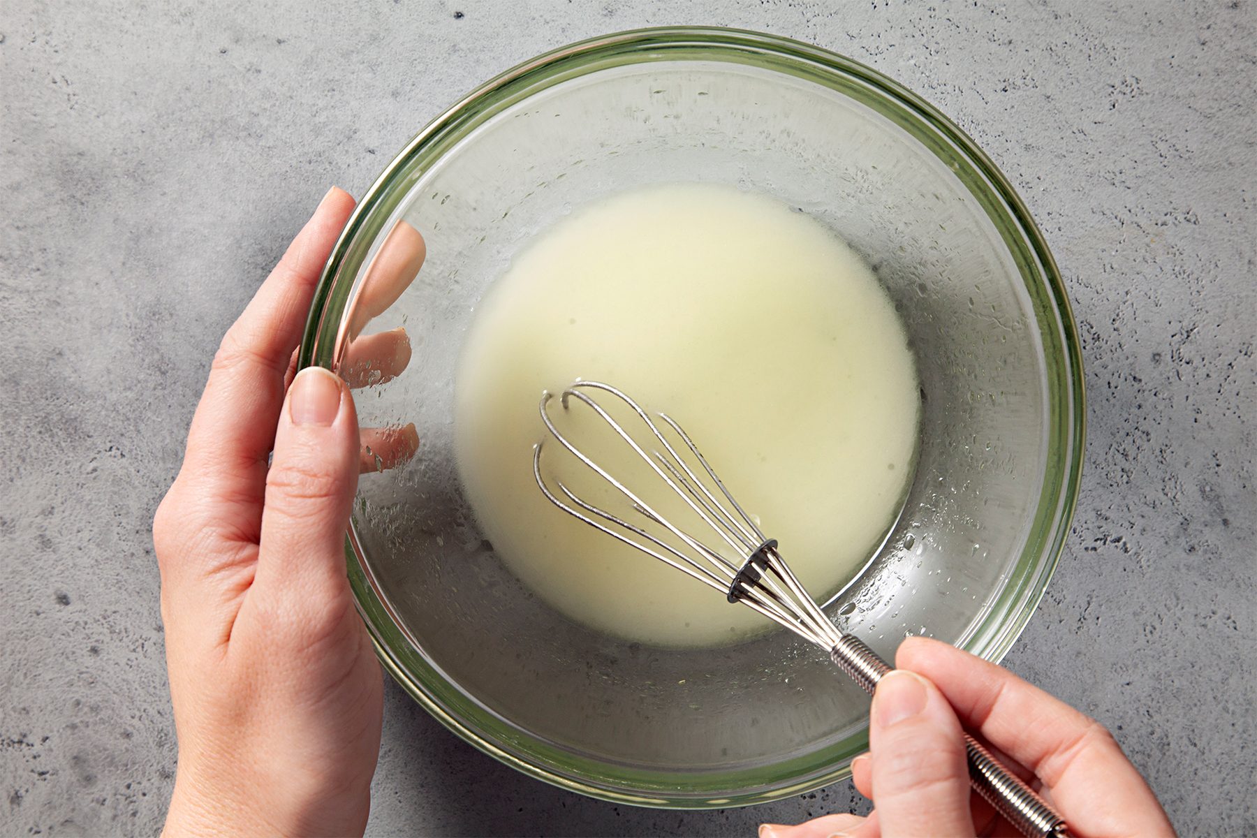 a person whisking oil and vinegar until blended