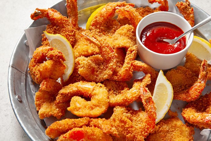 Butterfly Shrimp in a large plate with cocktail sauce and lemon wedges