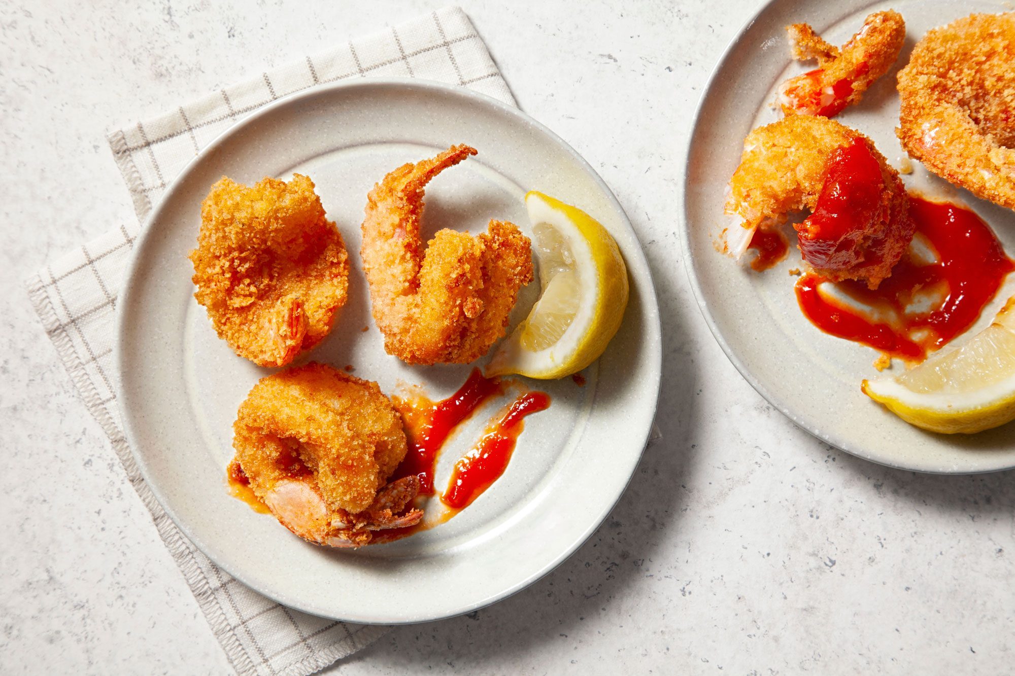 Butterfly Shrimp in a small plate with cocktail sauce and lemon wedges
