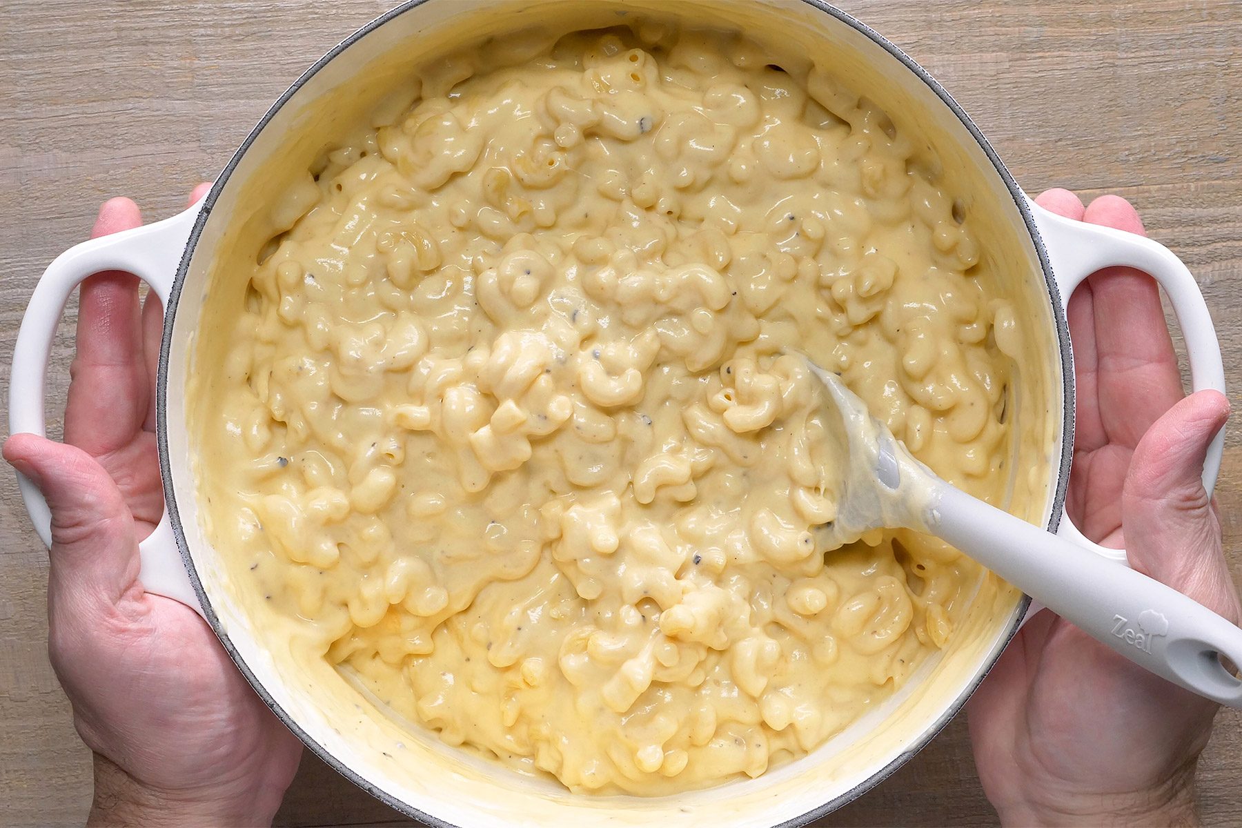 overhead shot; wooden background; added macaroni in cheese mixture in a pan;