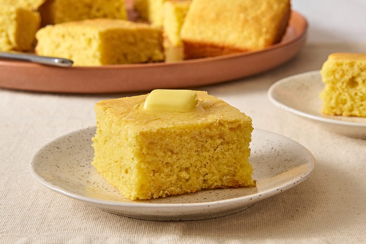 Closeup of a single square of sweet cornbread topped with butter