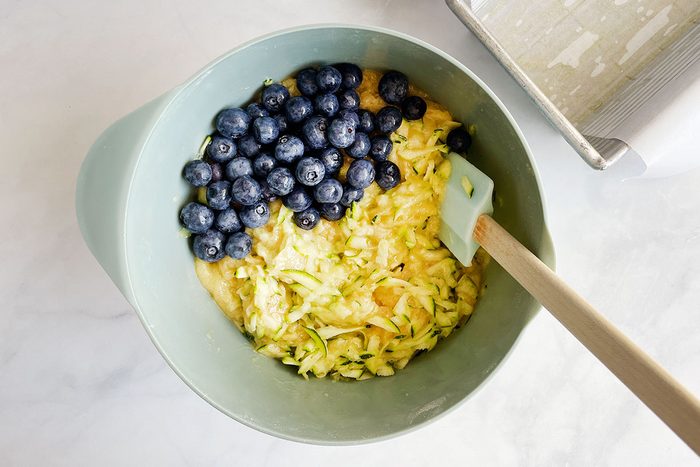 Step two in making Taste of Home's Blueberry Zucchini Bread involves stirring in blueberries and zucchini