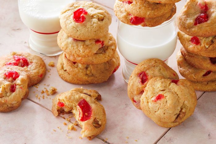 Cherry Cookies served with a glass of milk on a pink tile background