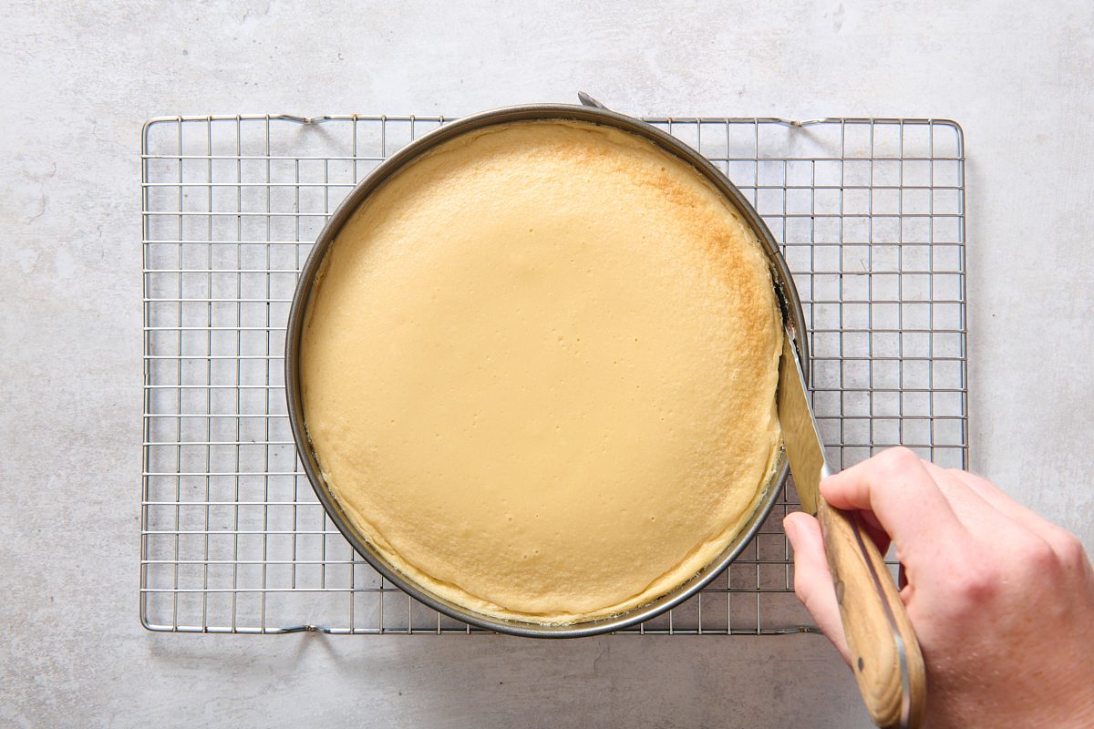 Running a knife around the edge of the cooked cheesecake