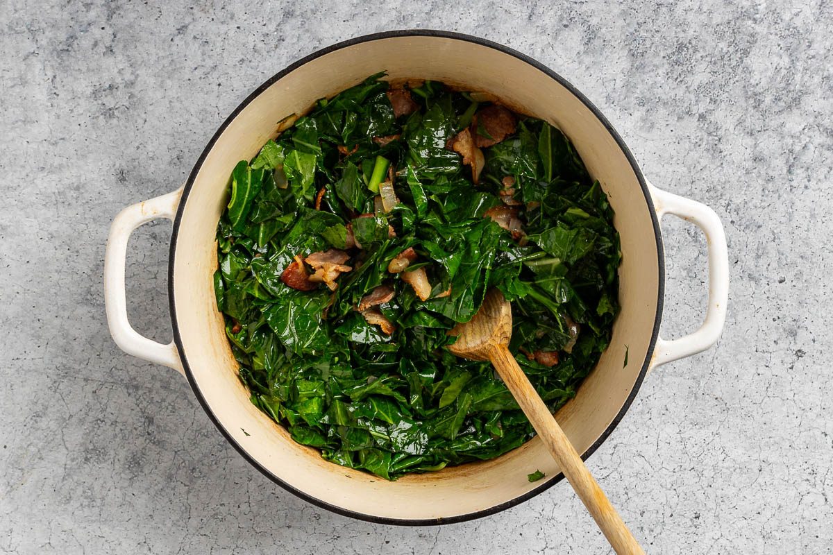 Taste of Home Collared Greens with Bacon recipe photo of the bacon and onion sauteed in a dutch oven with the collard greens added to the pot.