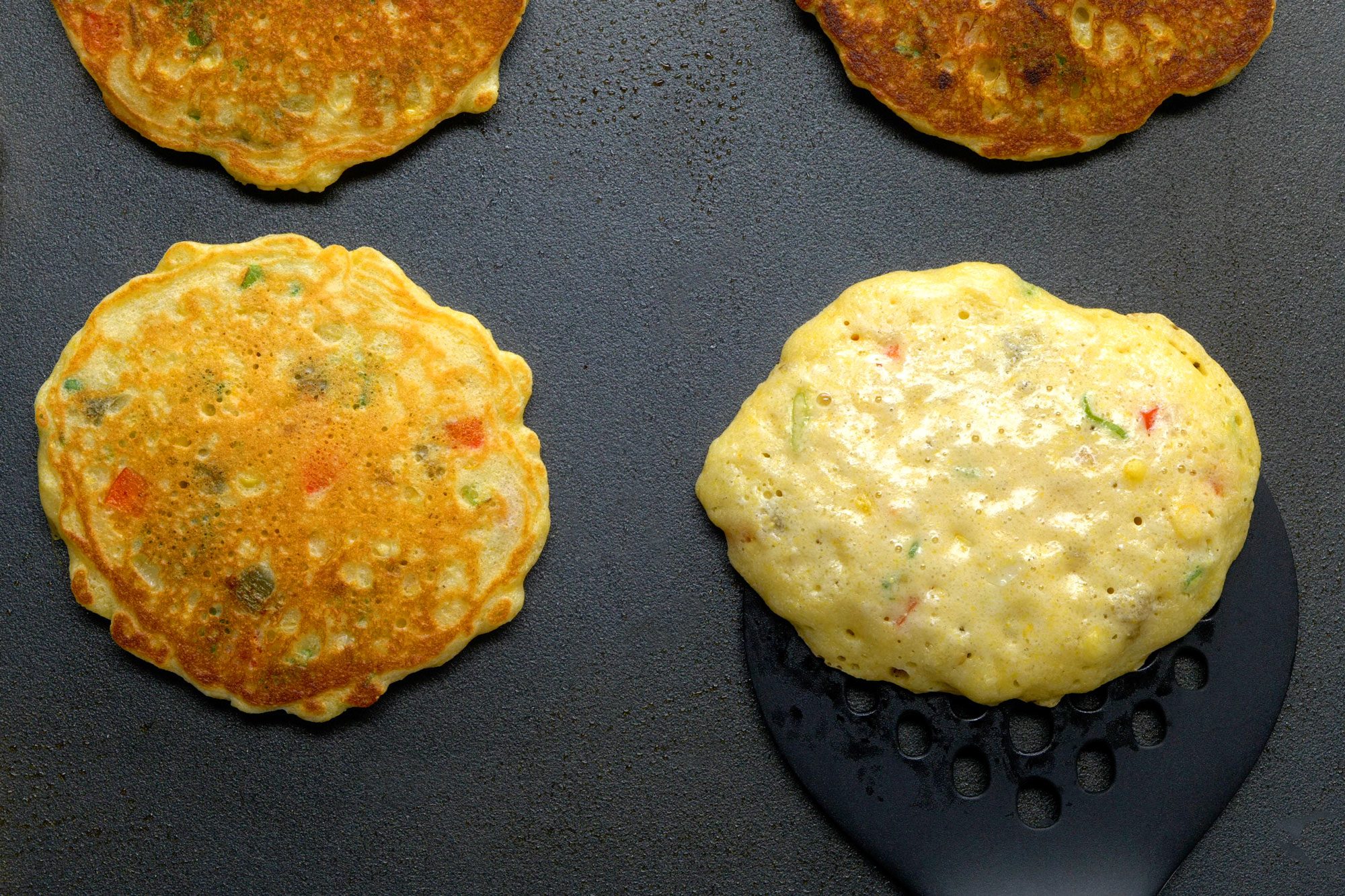 overhead shot; black background; cooking corn cakes untill golden brown;