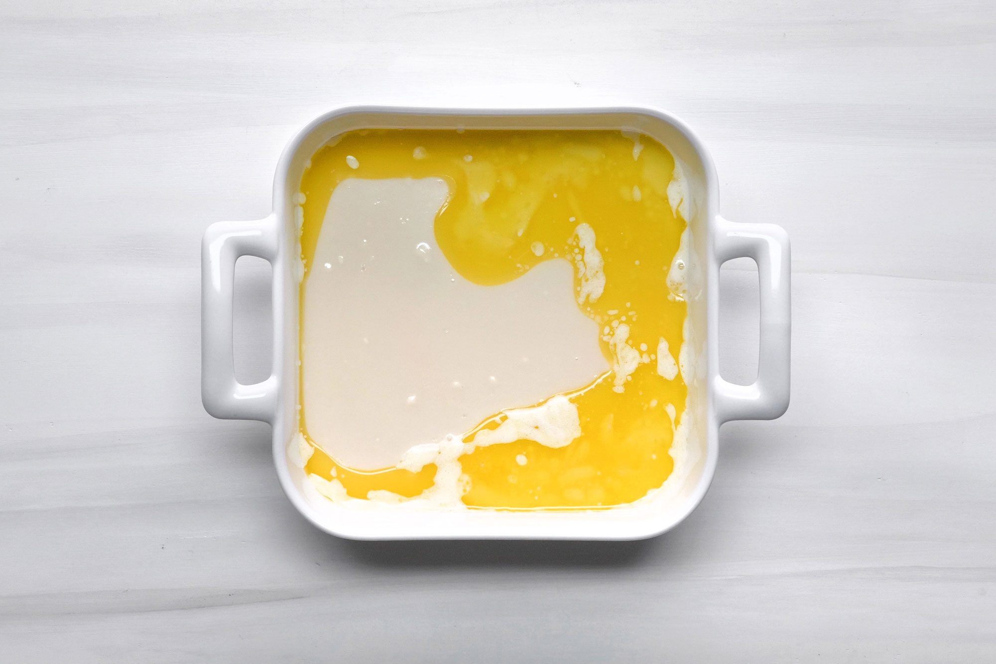 overhead shot; white background; Poured over butter in baking dish;