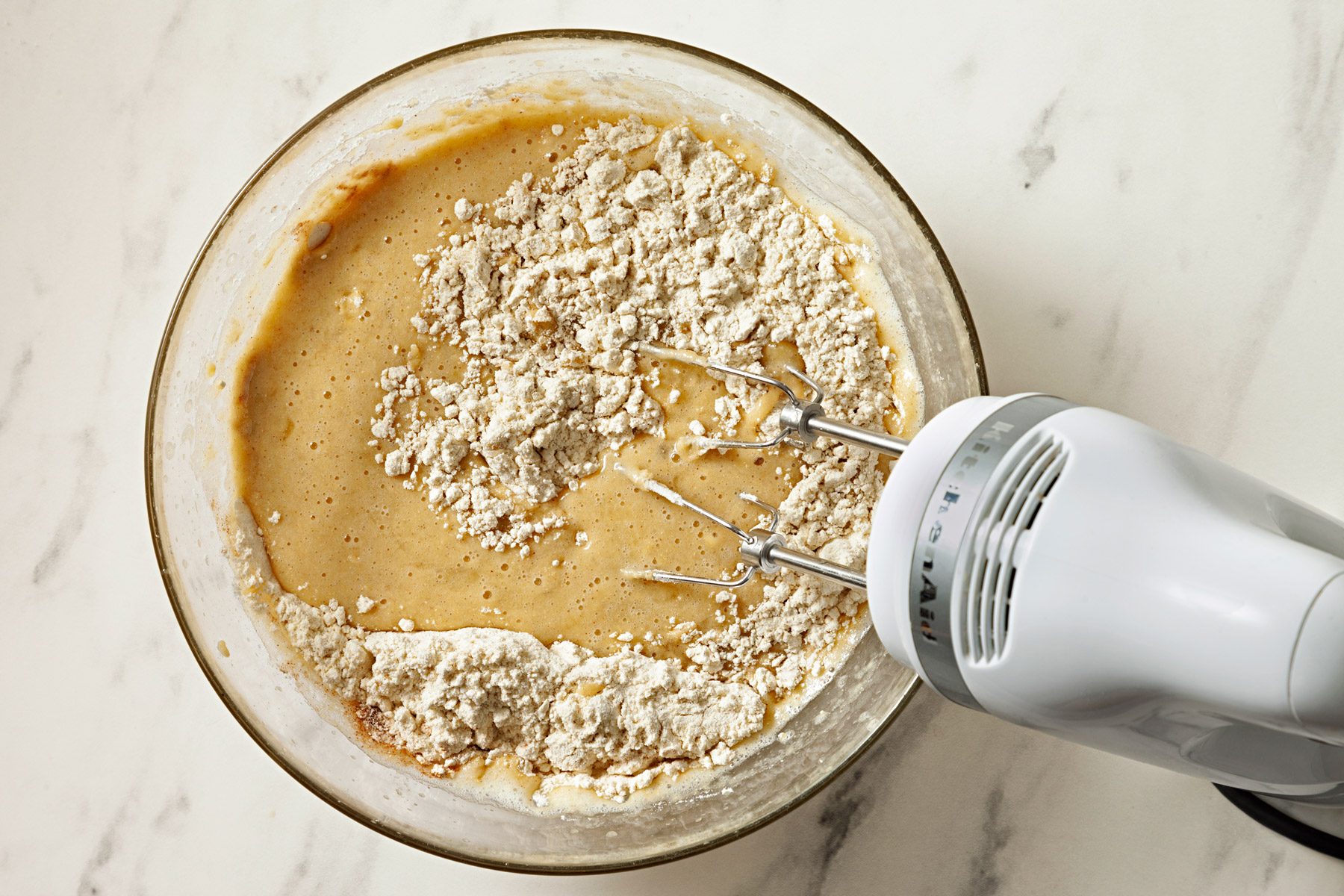 Banana mixture and flour mixture are combined in a bowl.