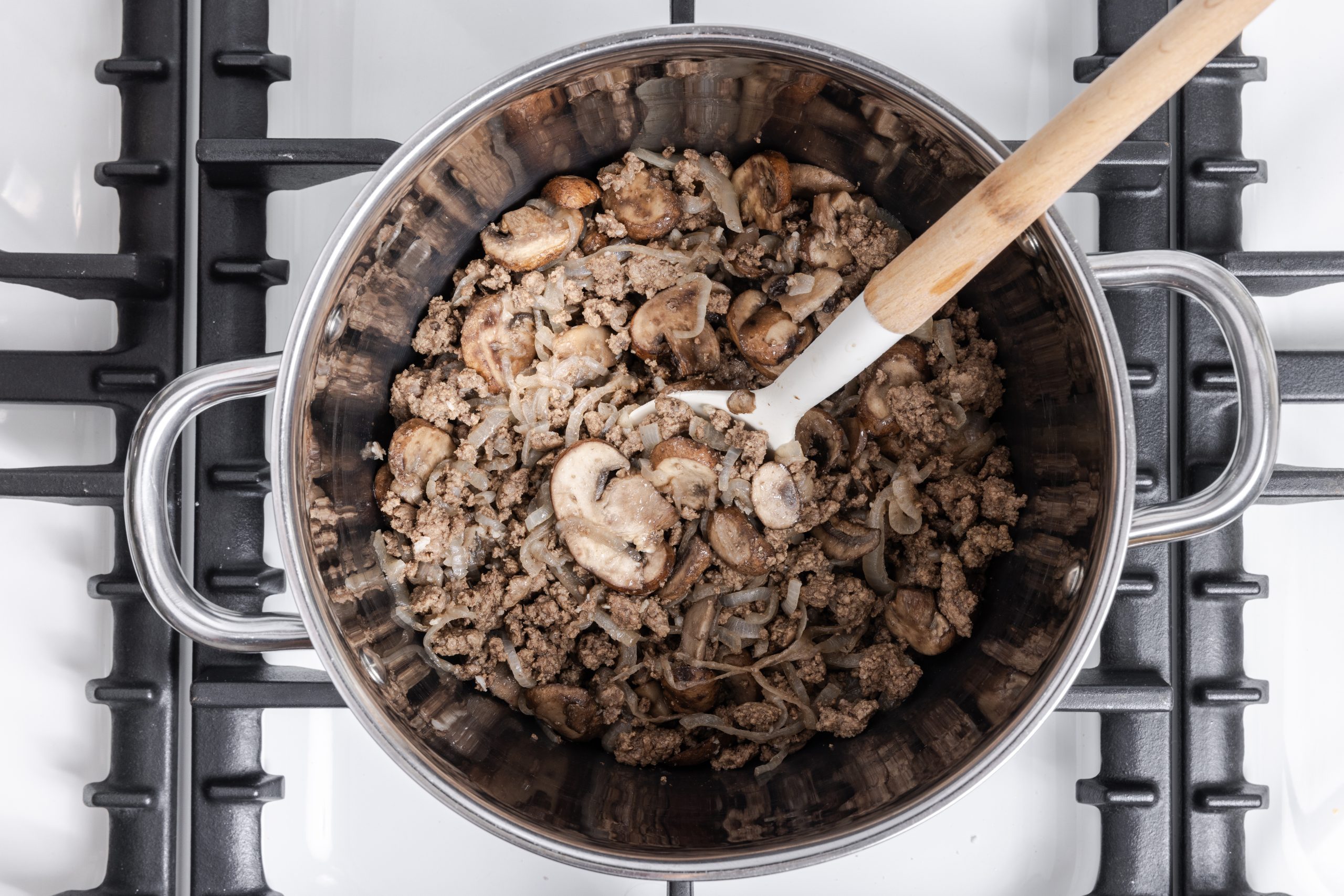 Ground beef, mushrooms and onions being cooked on stove top.