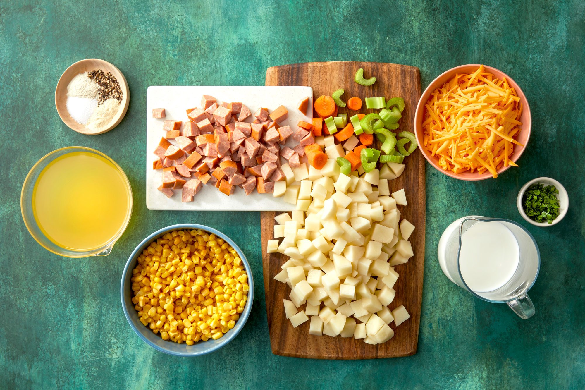 Overhead shot of all ingredients for Sausage Potato Soup; green texture surface;