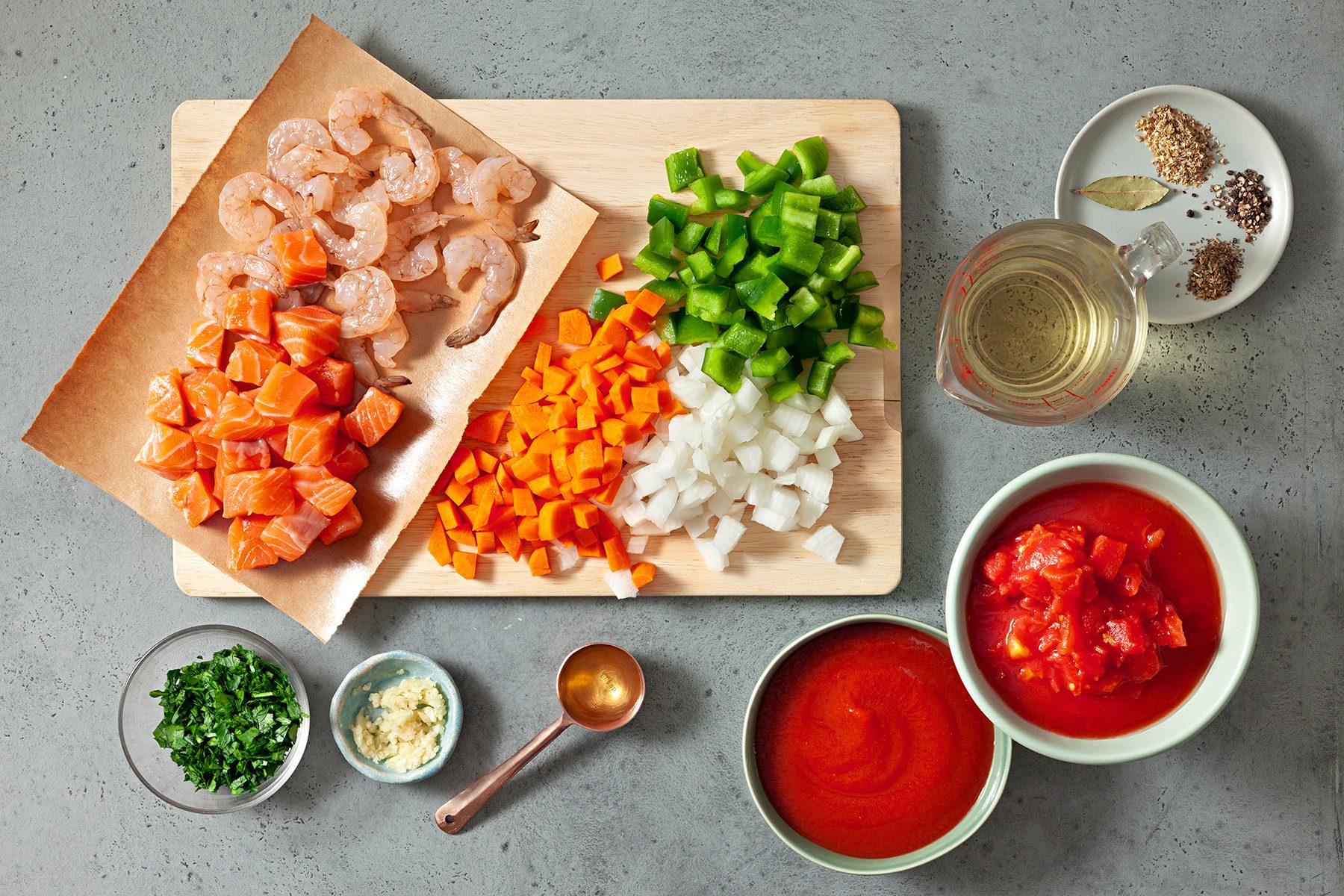 overhead shot; grey background; Seafood Soup ingredients placed on a wooden board and background;