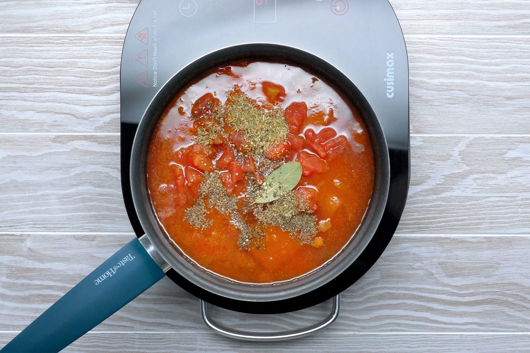 Overhead shot of a saucepan; stir in tomato sauce; tomatoes; wine and seasonings; bring to a boil; reduce heat; induction; wooden background;