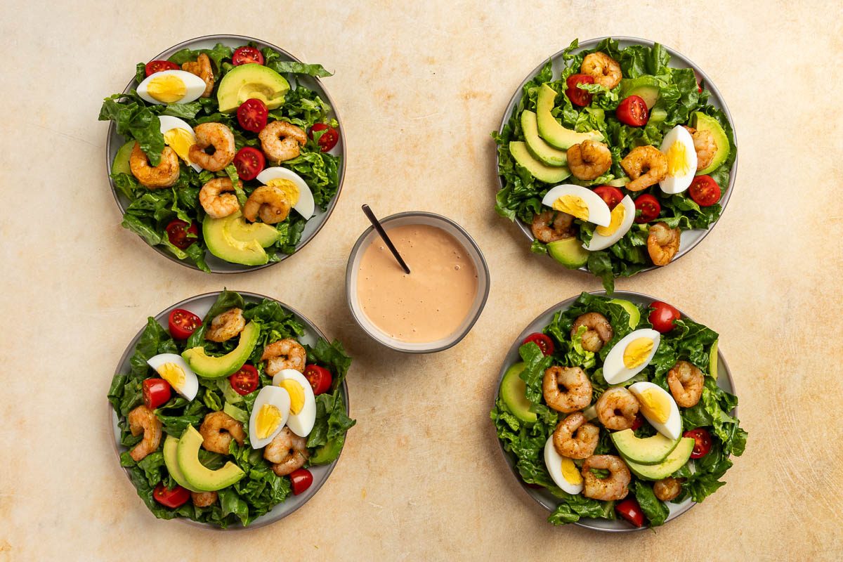 Taste of Home Shrimp Louie recipe photo of 4 plated salads with a side of the dressing.