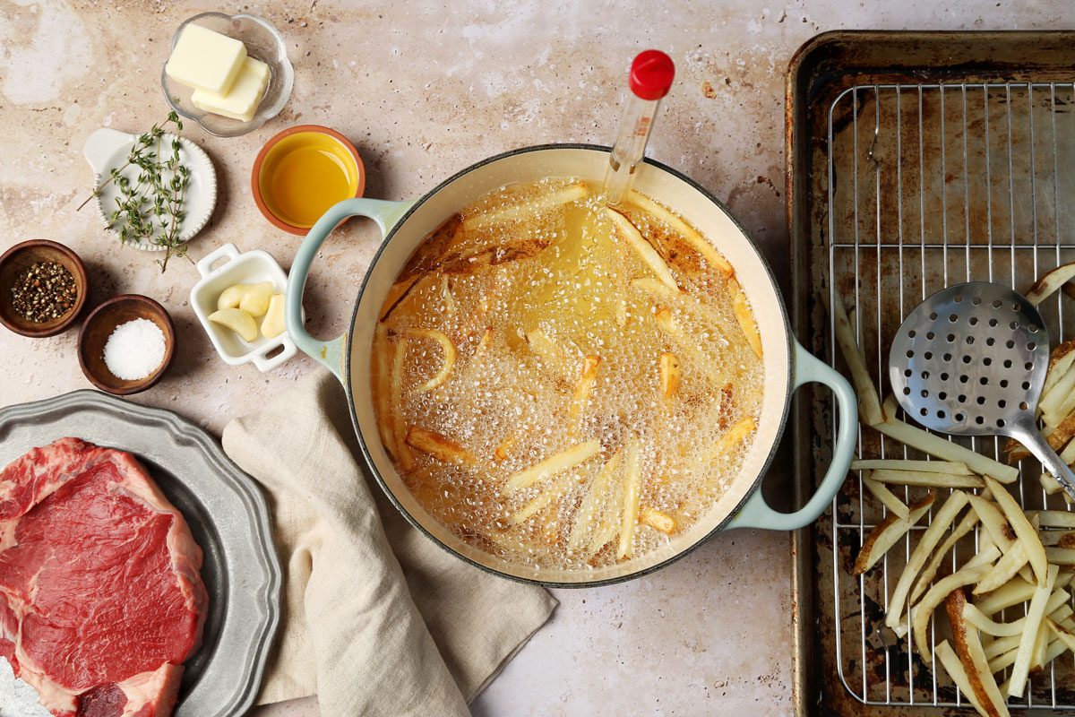 A how to look into Taste of Home's homemade Steak Frites. Cut up french fries being deep fried in oil in a dutch oven.