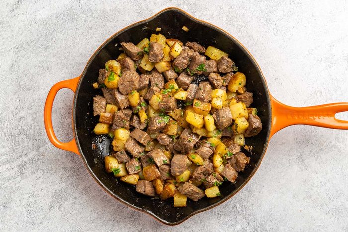 Taste of Home Steak and Potatoes recipe photo of the cooked steak and potatoes combined in the same pan and topped with fresh parsley.