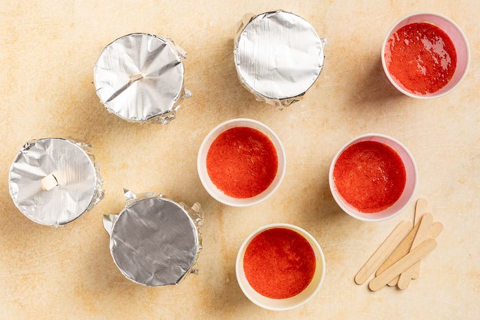 Taste of Home Strawbery Popsicles recipe photo of flilling the cups with the strawberry puree.