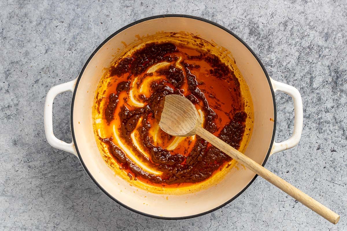 Taste of Home Thai Curry Soup recipe photo of the heated sesame oil with lightly sauteed red curry paste in a dutch oven.