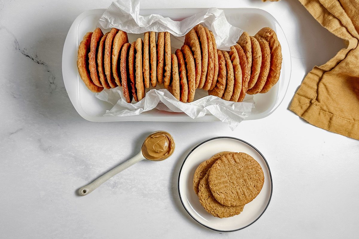 Taste of Home vegan peanut butter cookies in a white loaf pan and on a white ceramic plate.