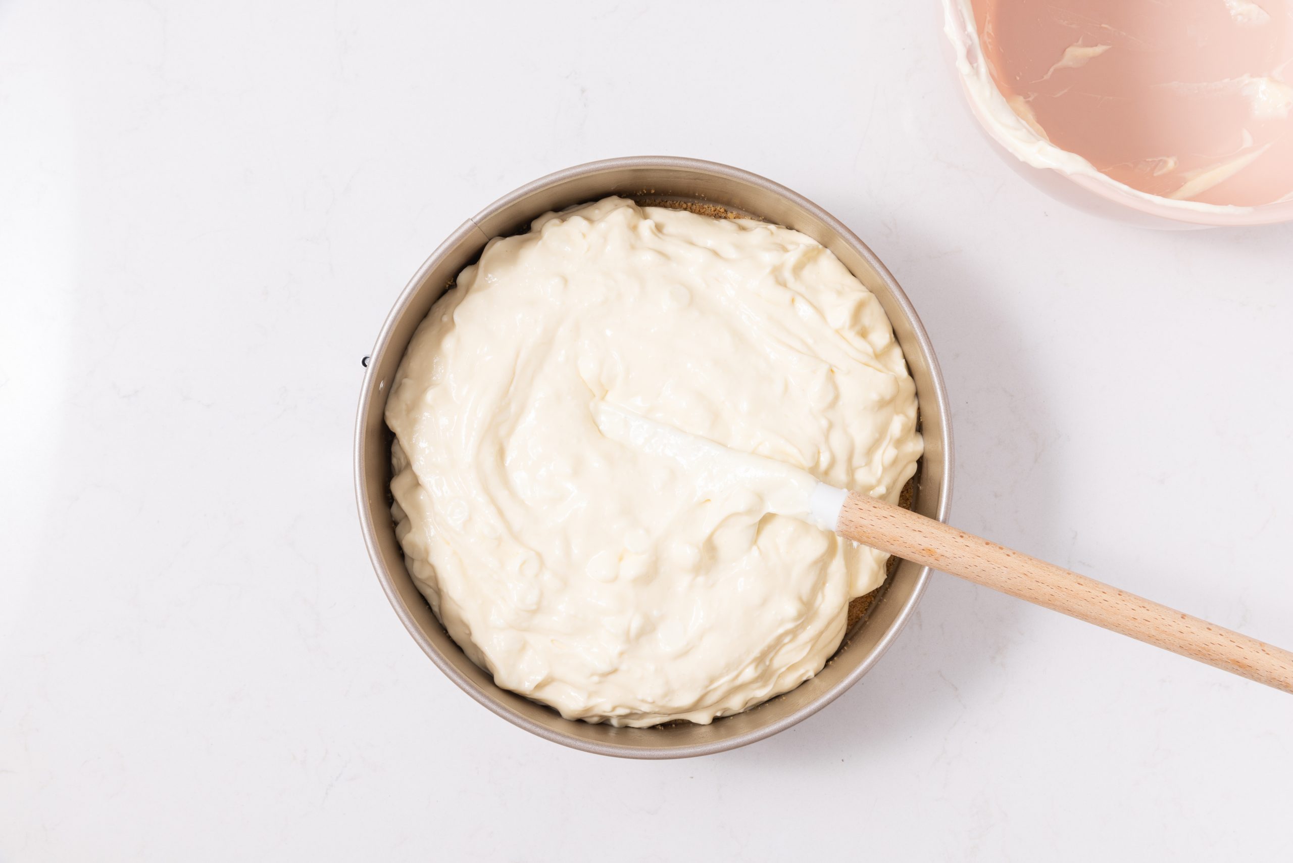 Filling of cheesecake being placed in springform pan.