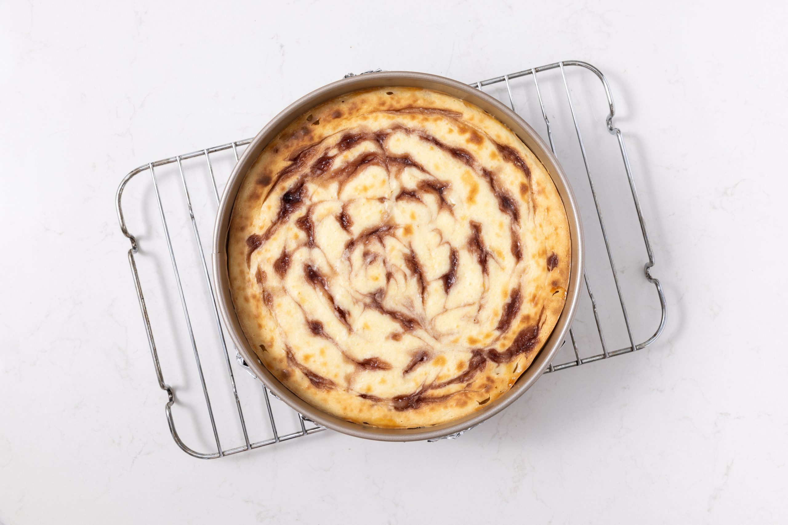 Cheesecake baked and cooling in wire rack.