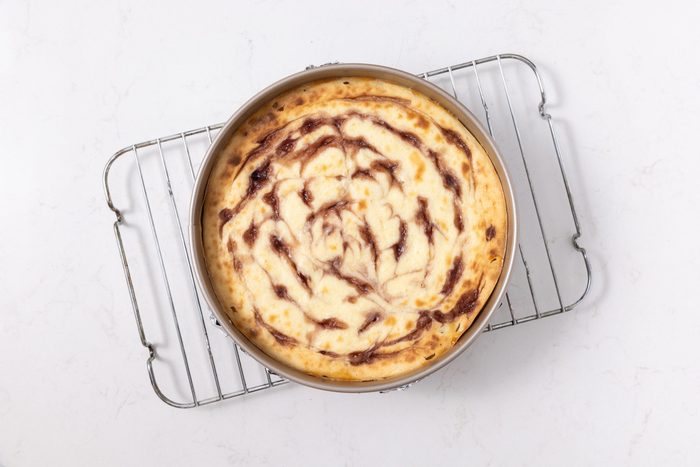 Cheesecake baked and cooling in wire rack.